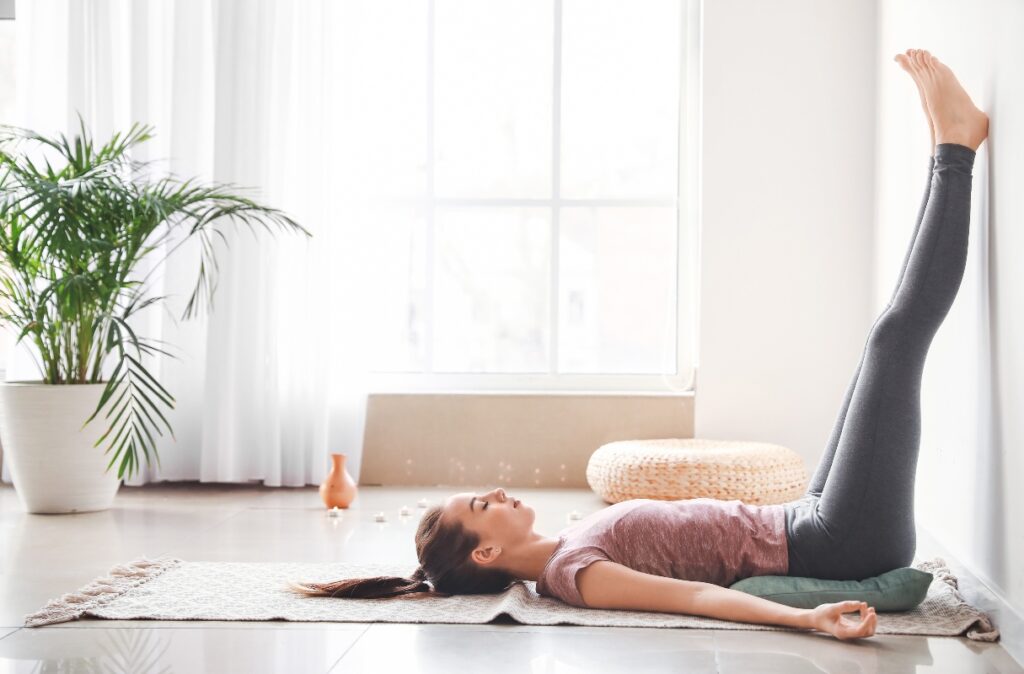 Esercizio di ginnastica posturale con gambe al muro per migliorare la circolazione e la postura. Tecnica rilassante per allineare la colonna vertebrale.